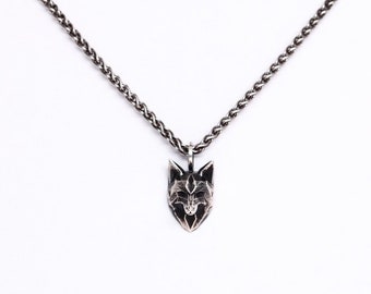 May include: A silver-toned pendant necklace featuring a detailed wolf head pendant. The pendant is intricately designed with visible facial features and is suspended from a matching chain. The necklace is displayed against a white background.