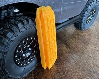 May include: Two orange plastic traction boards for off-road vehicles. The boards have a textured surface for grip.