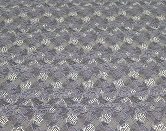 Puede incluir: Tela de encaje floral gris con un patrón delicado. El encaje tiene un brillo sutil y una textura suave.