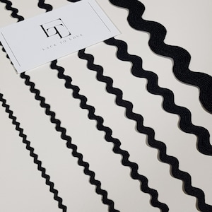 May include: Five black wavy trim ribbons of varying widths on a white background. The ribbons are arranged in a diagonal pattern. The text "Lace to Love" is visible in the top left corner of the image.