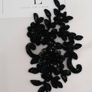 Può includere: Un'applicazione in pizzo nero con motivi floreali e a foglia, ricami intricati, piccole perline nere e paillettes. Il design è posizionato accanto a un cartoncino bianco con il testo LACE TO LOVE e un logo con le lettere L e T.