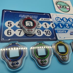 May include: A collection of Digimon card game accessories, including player number cards and acrylic Digivice tokens. The tokens are in various colors and feature the number "3". The game cards have the text "DIGIMON CARD GAME".