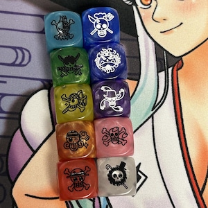 Op de afbeelding: Set van tien iriserende dobbelstenen met zwarte schedel- en kruisbeendesigns. Elke dobbelsteen heeft een ander personage uit de anime One Piece.