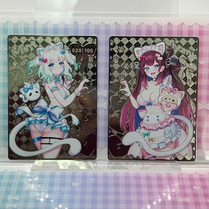 Puede incluir: Dos tarjetas coleccionables de estilo anime con personajes femeninos con atuendos con temática de gatos. La tarjeta de la izquierda tiene una combinación de colores blanco y azul, mientras que la tarjeta de la derecha tiene una combinación de colores rosa y blanco. Cada tarjeta tiene un fondo dorado y negro.