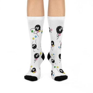 Può includere: Calzini bianchi con un design di personaggi dei cartoni animati in bianco e nero. Il personaggio è una creatura rotonda e soffice con due occhi e una piccola bocca. Il personaggio tiene una stella in ogni mano. I calzini hanno un polsino nero e una punta nera.