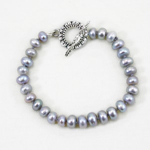 May include: A gray pearl bracelet with a silver toggle clasp.