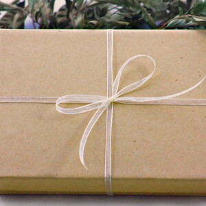 May include: A brown gift box tied with a white ribbon and bow.