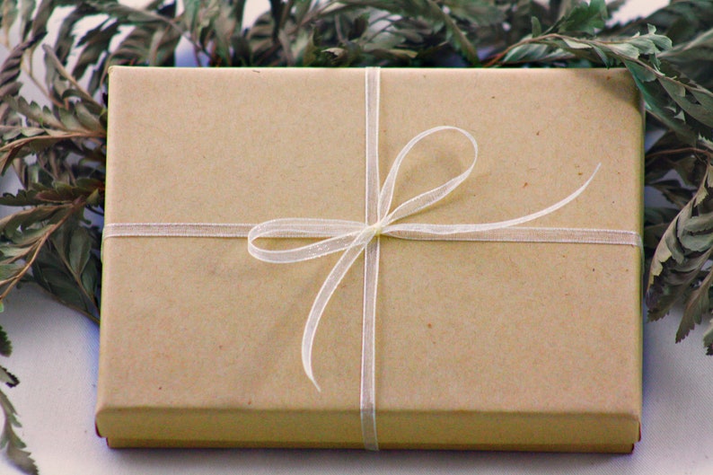 May include: A brown gift box tied with a white ribbon and bow.