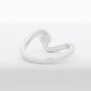 May include: A silver wave ring. The ring is made of a single piece of metal that is bent into the shape of a wave.