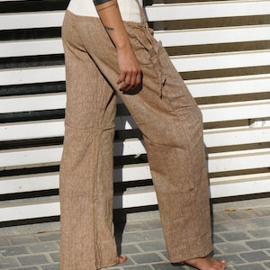 May include: Brown linen pants with a white elastic waistband and a drawstring closure. The pants have a relaxed fit and are perfect for a casual look.