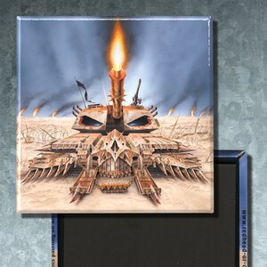May include: A rectangular magnet featuring a detailed illustration of a futuristic tank with a large cannon firing a flame. The artwork is set in a desert landscape with smoke and flames. The magnet has a black backing and a blue border. Text includes "Inks and acrylics painting on Art" and "Copyright © 2021 by Eric PHILIPPE - All rights reserved."