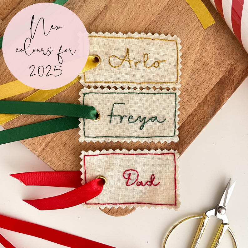 Three name tags with hand embroidered names, in gold, emerald green and dark red for Christmas presents
