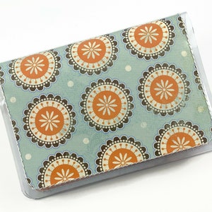 May include: A clear plastic card holder with a blue and orange patterned design. The pattern features repeating circles with a white center and a brown border.