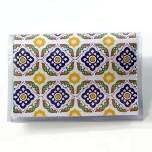 May include: A clear plastic wallet with a white background and a colorful pattern of blue, yellow, and green geometric shapes. The pattern resembles a tiled floor.