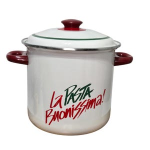May include: A white enamel stockpot with a matching lid, featuring dark red side handles and a dark red lid knob. The pot displays the green and red text La PASTA BUONISSIMA! on the front, with a thin green line circling the lid rim.