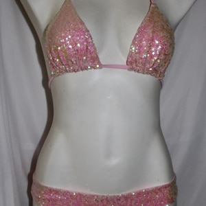 May include: Pink sequined bikini top and bottom. The top is a triangle style with adjustable straps. The bottom is a cheeky style with a low rise.