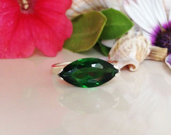 May include: A silver ring with a large, marquise-shaped, emerald green gemstone.