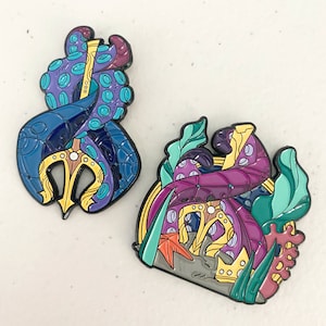 May include: Two enamel pins featuring a purple and blue octopus with a trident and a purple octopus with a crown. The octopus pins are surrounded by seaweed and coral.