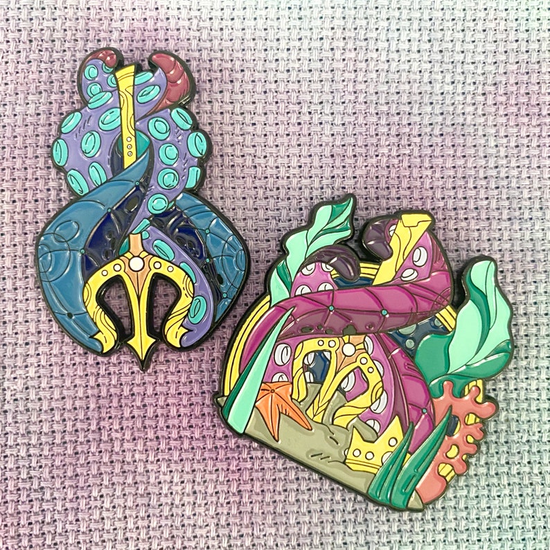 May include: Two enamel pins featuring an octopus with a trident and an octopus with a seashell. The octopus with the trident is blue, purple, and yellow. The octopus with the seashell is pink, purple, and green.