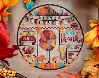 May include: A cross-stitch embroidery design featuring a turkey, pumpkins, and the words "Happy Thanksgiving" and "Give Thanks". The design is surrounded by fall leaves and a sunflower.