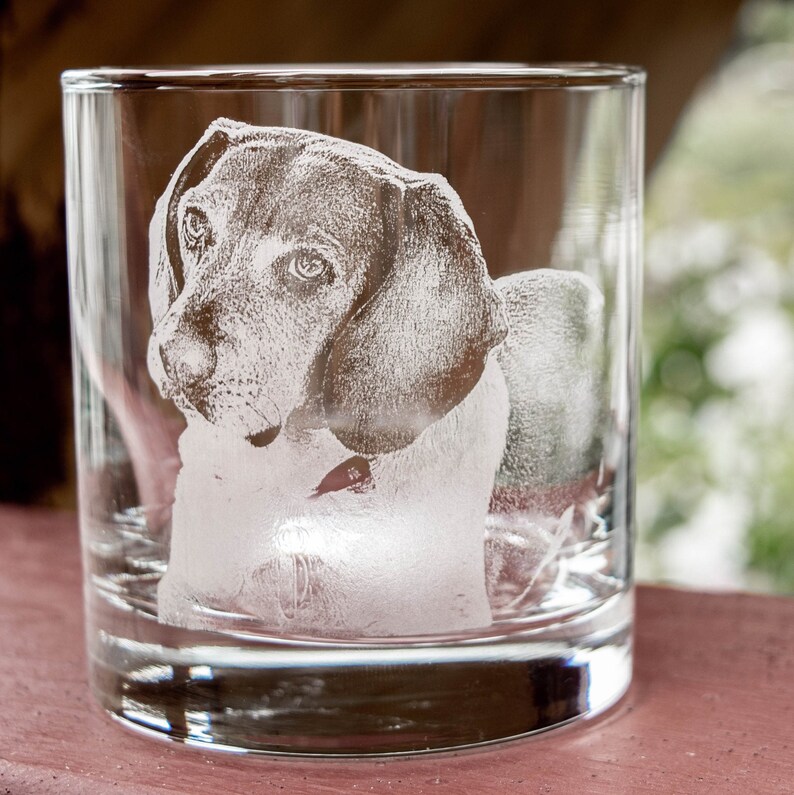 May include: A clear glass tumbler with an etched image of a dog's head. The dog is a beagle with floppy ears and a serious expression.