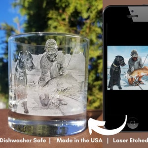 May include: A personalised glass with a laser-etched image of a person fishing with a dog. The image is in black and white and the glass is clear. "Dishwasher Safe | Made in the USA | Laser Etched" is printed on the bottom of the image.