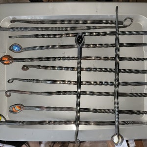 May include: A set of 12 metal fireplace pokers with twisted handles. Each poker has a different colored glass marble attached to the end.