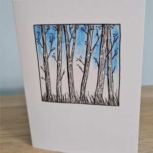 Puede incluir: Una ilustraci&oacute;n en blanco y negro de un bosque con un fondo de acuarela azul. Los &aacute;rboles son altos y delgados con ramas que se extienden hacia el cielo.