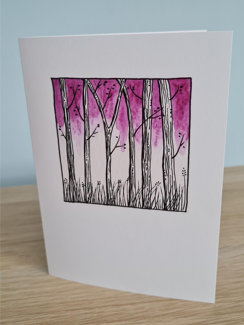 Puede incluir: Una pintura de acuarela de una escena de bosque con un fondo degradado rosa y morado. Los &aacute;rboles est&aacute;n delineados en tinta negra y tienen peque&ntilde;as ramas.