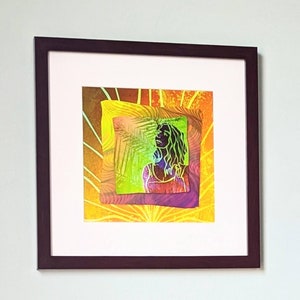 Peut inclure: Une estampe d'art abstrait encadrée avec une silhouette de femme au centre. L'arrière-plan est un design superposé de jaune, orange, vert et violet.