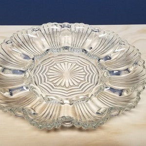 May include: A clear glass serving dish with a scalloped edge and a center section with a starburst pattern. The dish has eight individual sections around the center.