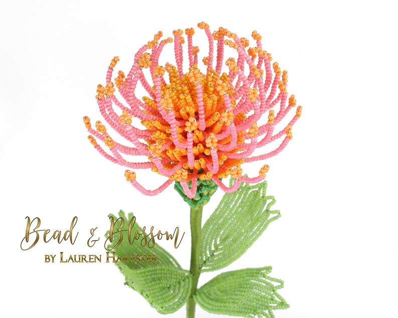 May include: A beaded flower with pink and orange petals and green leaves. The flower is made of small beads and is a realistic representation of a real flower. The flower is on a white background. Bead & Blossom by Lauren Harpster.
