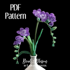 Könnte beinhalten: Ein PDF-Muster für einen Perlen-Freesie-Blumenstrauß. Der Strauß steht in einer weißen Vase und hat lila und grüne Perlen.