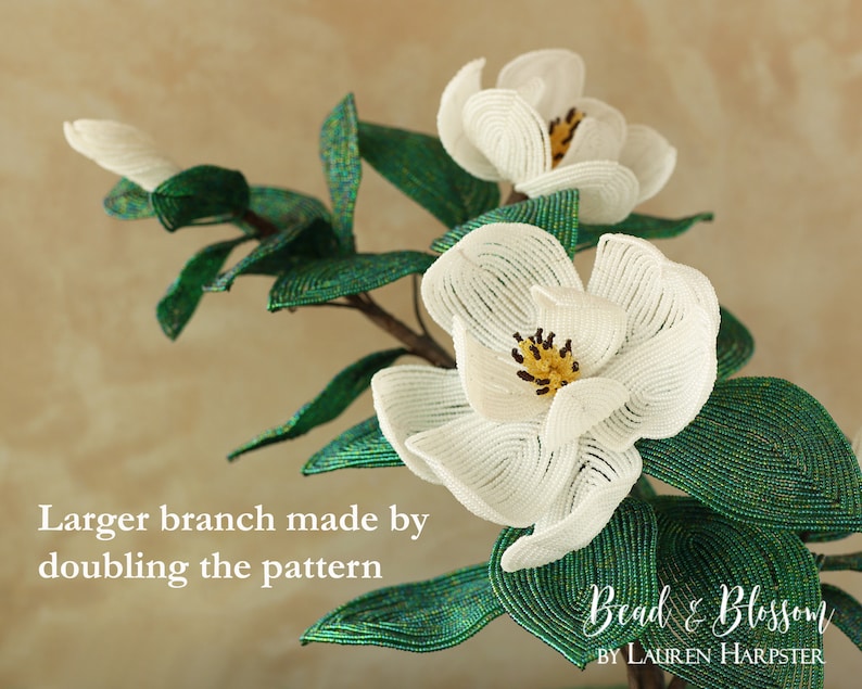 May include: A close-up of a beaded magnolia flower branch with green leaves. The branch is made by doubling the pattern. The text "Bead & Blossom by Lauren Harpster" is visible in the bottom right corner of the image.