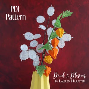 May include: PDF pattern for a beaded flower arrangement featuring white and orange flowers in a yellow vase. The flowers are made with beads and wire. The text "Bead & Blossom by Lauren Harpster" is at the bottom of the image.