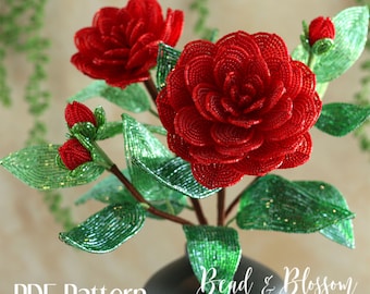 May include: A PDF pattern for a beaded camellia flower, featuring a red camellia with green leaves. The pattern is by Bead & Blossom by Lauren Harpster.