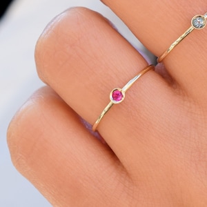 Peut inclure: Deux anneaux délicats en or avec de petites pierres précieuses. L'un a une pierre rouge et l'autre une pierre claire.