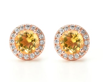 May include: A pair of gold earrings with a round, yellow gemstone surrounded by a halo of smaller, white gemstones.