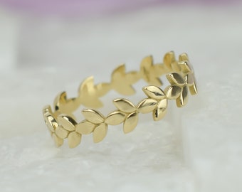 Könnte beinhalten: Ein goldener Ring mit einem zarten Design aus Blättern um das Band.