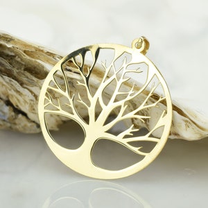 May include: A gold-toned pendant in the shape of a tree of life. The pendant is circular and has a delicate, intricate design.