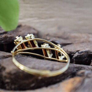 May include: A gold ring with a design of multiple black gemstones set in a gold band.