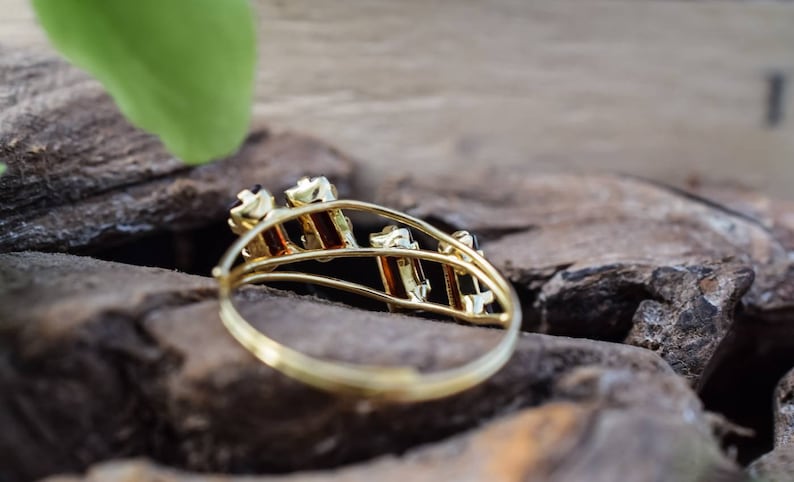 May include: A gold ring with a design of multiple black gemstones set in a gold band.