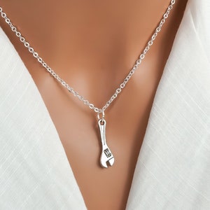 May include: A silver chain necklace with a silver wrench pendant.