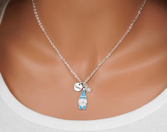 May include: A silver-toned chain necklace featuring a small pendant shaped like a gnome with a blue hat and white beard, accompanied by a circular charm engraved with the name Casey and a small clear crystal accent charm.