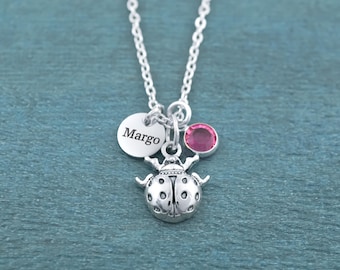 May include: A silver-toned necklace featuring a ladybug charm, a small circular disc engraved with the name Margo, and a single round pink crystal charm. The pendant hangs from a delicate silver-toned chain with a polished metallic finish.