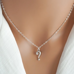 May include: A silver chain necklace with a question mark pendant.