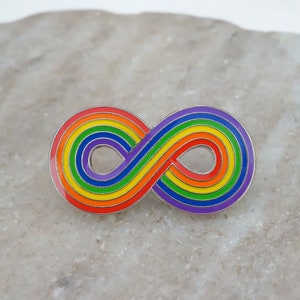 May include: A rainbow infinity symbol pin. The pin is made of metal and has a silver finish. The rainbow colours are red, orange, yellow, green, blue, indigo, and violet.