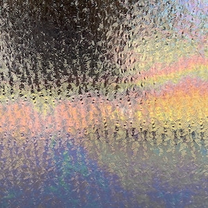 May include: A close-up of a textured glass surface with a rainbow-like iridescent sheen. The glass has a pattern of small, raised circles.