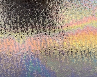 May include: A close-up of a textured glass surface with a rainbow-like iridescent sheen. The glass has a pattern of small, raised circles.