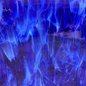 May include: Abstract close-up of a sheet of stained glass. The glass features a swirling pattern of deep blue and lighter shades of blue, creating a dynamic, flowing effect. The texture is smooth and reflective.